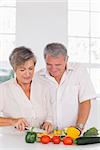 Elderly couple preparing vegetables in kitchen