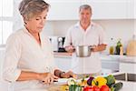 Old couple preparing food in kitchen