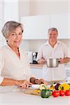 Old lovers preparing food in kitchen