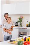 Grandmother taking her grandson in her arms in kitchen