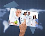 Hand selecting image of doctor holding apple on blue world map background