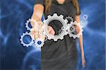 Busineswoman touching graphic wheels and cogs on blue digital background