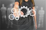 Busineswoman touching illustrated wheels and cogs on grey digital background
