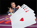 Gambler holding whiskey at poker table with digital hand of four aces in foreground