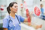 Nurse touching screen showing red ECG data in hospital ward