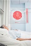 Elderly patient lying in hospital bed with futuristic ECG data display in a hospital ward