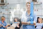 Smiling nurse standing behind blue display screen showing pelvic xray in hospital ward