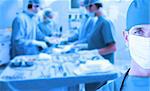 Portrait of a doctor standing in operating room in front of an operation on a blue background