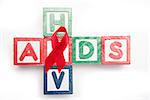 Wood blocks spelling aids and hiv in a cross shape with red awareness ribbon on white background