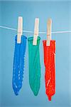 Three condoms hanging on line on blue background