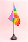 Gay Pride flag on stand on pink background
