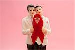Gay groom cake toppers with red awareness ribbon on pink background