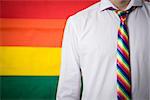 Man wearing shirt and rainbow tie on rainbow flag background