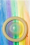 Rolled up condom on gay pride rainbow brush stroke