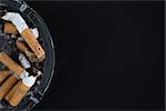 Ashtray full of butts with copy space on black background