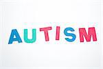 Autism spelled out in pink green and blue on white background
