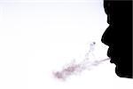 Silhouette of man blowing smoke with white copy space