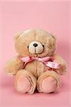 Teddy bear with pink ribbon on pink background