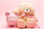 Teddy bear and piggy bank on pink background