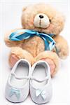 Teddy bear with blue ribbon and white booties on white background