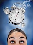 Woman looking up at ringing alarm clocks on blue background