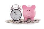 Piggy bank beside alarm clock on dollars on white backgroun