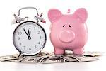 Pink piggy bank beside alarm clock on dollars on white background