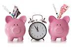 Dollar and euro notes and syringes sticking out of piggy banks with alarm clock on white background