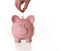 Hand putting coin into piggy bank with copy space on white background