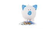 Blue and white hand painted piggy bank standing on euro notes and coins