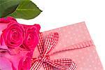 Pink roses leaning on pink polka dot wrapped present on white background