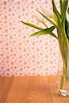 Vase of tulips on wooden table with wallpaper background