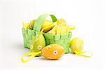 Easter eggs wrapped in foil in a green wicker basket