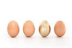 Four eggs in a row with one gold one on white background