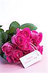 Bouquet of pink roses with happy mothers day card on a light pink table