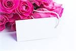 Close up of a beautiful bouquet of pink roses with a blank card on a white table