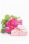 Bouquet of pink roses next to a gift with a happy mothers day card on a white table