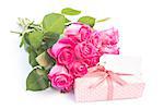 Bouquet of roses next to a gift with a blank card on a white table