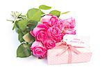 Bouquet of pink roses next to a gift with a happy birthday card on a white table