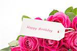 Close up of a bouquet of pink roses with a happy birthday card on a white background