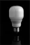 Energy saving light bulb standing on black background close up