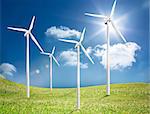 Four wind turbines in a green field in the sunshine