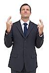 Serious businessman with fingers crossed is looking up on white background