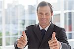 Smiling businessman giving thumbs up in an office