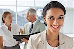 Cheerful businesswoman in front of colleagues working behind on a folder