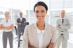 Attractive businesswoman with arms crossed standing in front of colleagues