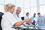 Two smiling doctors looking at a laptop in office