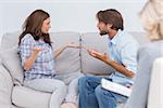 Couple going through therapy and crying on the couch as therapist listens