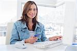 Cheerful woman purchasing online with her credit card in modern office