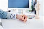 Female hands drawing with pencil on paper on her desk